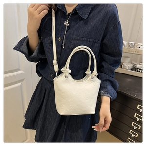Detailed view of white embossed leather bucket bag with cartoon heart patterns on model