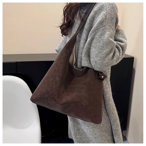 Detail of dark brown tote bag showing vintage leather texture and white contrast stitching