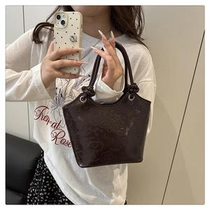 Detailed view of coffee brown embossed leather bucket bag with heart and Love patterns