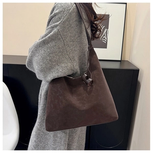Detailed view of deep brown suede tote bag with contrast stitching and knotted strap detail