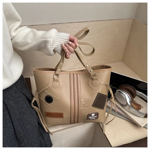 Detailed view of khaki tote bag featuring retro patches and decorative side drawstrings