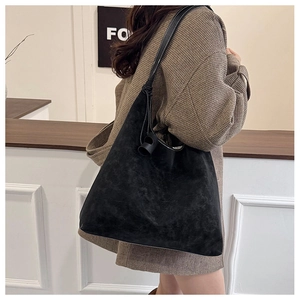 Detail showing the matte texture and round buckle of the large black shoulder bag