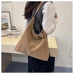 Close-up of a khaki suede tote bag with a matching round charm for casual daily wear