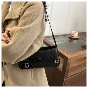 Detail of minimalist black leather underarm bag with double cross belts and silver buckles