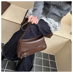 Detail of dark brown leather shoulder bag with decorative belts and bow buckle accents