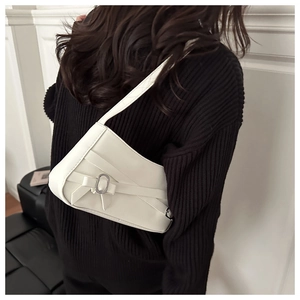 Close-up of white leather shoulder bag with asymmetrical shape and bow detail