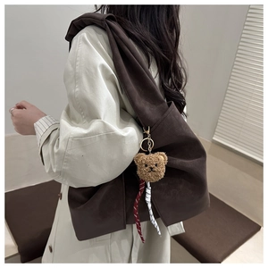 Detail of dark brown tote bag with cute teddy bear charm and soft suede texture