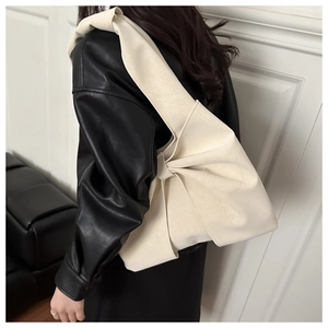 Detailed view of the large decorative bow on a cream white leather tote bag