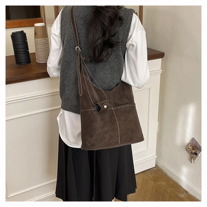 Detail shot of a large brown faux suede tote bag with contrast stitching and pocket