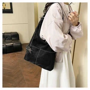 Detail of black tote bag with white contrast stitching and side snap pocket shown on model