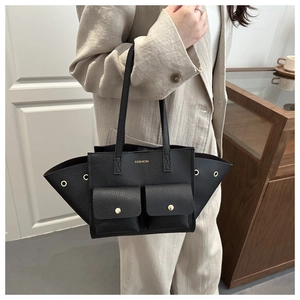 Dettaglio della grande borsa tote in pelle nera con design alato e tasche frontali