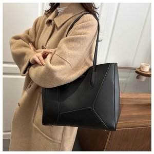 Close-up of black matte leather tote bag with geometric stitching on wool coat model