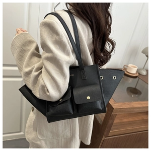 Dettaglio della borsa nera in pelle martellata con tasche dorate su un blazer beige