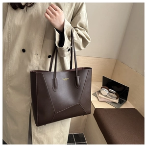 Detail of a dark brown leather tote bag with gold logo and stylish stitching details