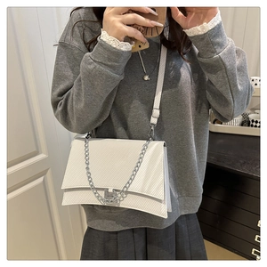 Détail d'un sac blanc texturé avec boucle logo B argentée et bandoulière chaîne
