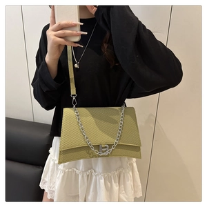 Détail du sac bandoulière tissé vert moutarde avec chaîne argentée et boucle en B