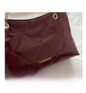 Dettaglio della borsa tote trapuntata bordeaux con catena dorata e texture lucida