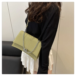Détail du sac bandoulière tressé vert avec boucle métallique argentée en B et chaîne