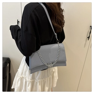 Détail du sac baguette bleu-gris texturé avec logo B argenté et chaîne sur mannequin