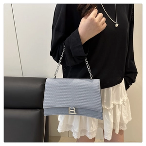 Détail du sac à chaîne bleu clair à texture tissée avec logo B et forme sablier