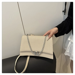 Détail du sac tressé beige avec boucle argentée en B et bandoulière en chaîne