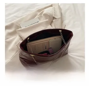 Vista dall'alto dello spazioso interno di una borsa shopper trapuntata bordeaux con oggetti