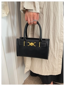 Primo piano di una borsa in pelle nera con chiusura vintage a cuore in metallo dorato