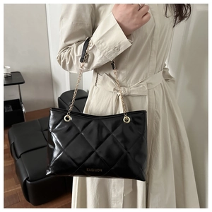 Dettaglio della borsa nera trapuntata con catena dorata e scritta FASHION