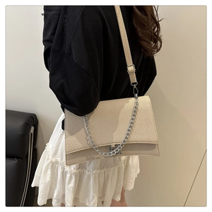 Détail du sac beige à motif pied-de-poule avec chaîne argentée et bandoulière large