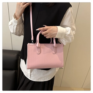 Dettaglio della borsa rosa con trama a pieghe verticali e accenti in metallo argentato