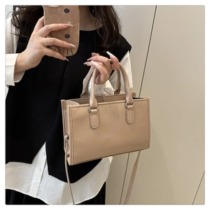 Dettaglio della trama plissettata beige e delle parti metalliche argentate della borsa