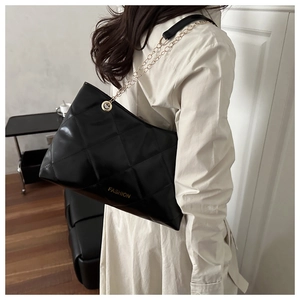 Dettaglio borsa shopper nera trapuntata con catena dorata e scritta Fashion elegante
