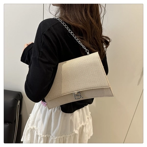 Détail du sac beige tressé avec chaîne et logo B argenté porté par un mannequin