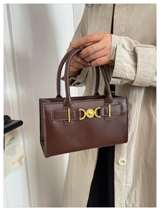 Dettaglio della borsa marrone vintage con una fibbia dorata incisa con un cuore