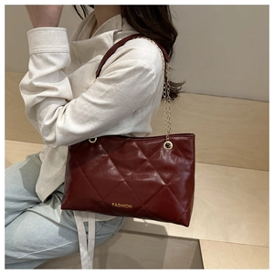 Dettaglio della borsa tote bordeaux trapuntata con catena dorata e logo moda