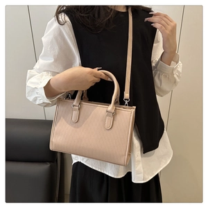 Dettaglio della texture a rilievo verticale e inserti in argento della borsa beige