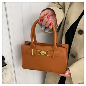 Vista dettagliata della borsa in pelle color cammello con fibbia a cuore dorata