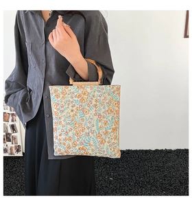 Close-up of vintage floral tote bag with textured knit fabric and natural bamboo handles