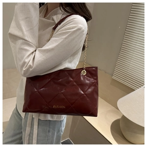 Dettaglio borsa shopper trapuntata bordeaux con catena dorata e logo moda