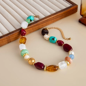 Detail of bohemian resin beaded necklace with gold metal spheres and faux pearl drop