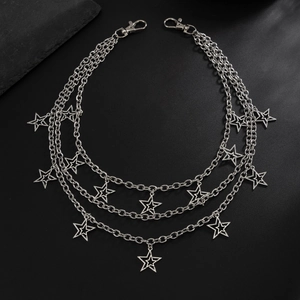 Detail of punk multi-layer star and cross charms with silver chains on black background
