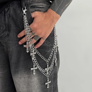 Detail of gothic multi-layer trousers chain with silver crosses on black jeans