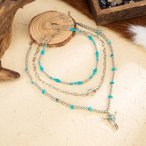 Detail of bohemian layered necklace featuring a silver bull head pendant and turquoise beads