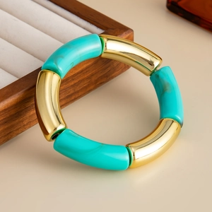 Detalle de pulsera elástica con tubos de resina turquesa y metal dorado estilo bambú