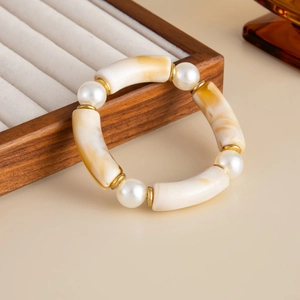 Detailed close-up of marble textured amber beads and pearls on elastic bracelet