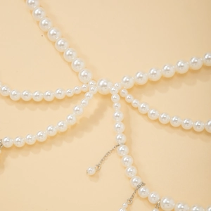 Dettaglio di perle bianche e catene d'argento su una catena per il corpo stile boho