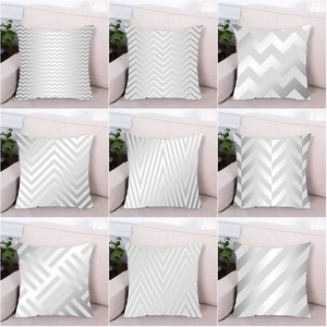 Detalle de fundas de cojín gris y blanco con motivos geométricos y textura metálica