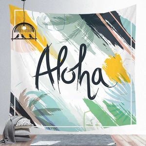 Close-up of tropical palm leaf tapestry featuring Aloha lettering on a white wall