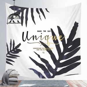 Detail of tropical leaf tapestry with unique quote hanging in a modern living room