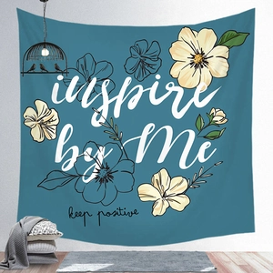 Detail of tropical floral tapestry with inspire by Me text against a blue background